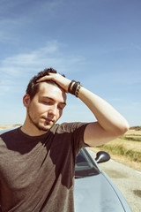 Hombre joven preocupado tras una avería de coche en un viaje 