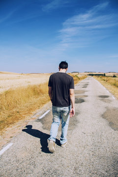 Hombre joven caminando por una carretera vacía 
