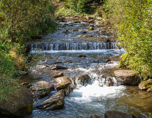 Fast flowing stream in the Carpathian Mountains overcoming rapids and ledges of rock