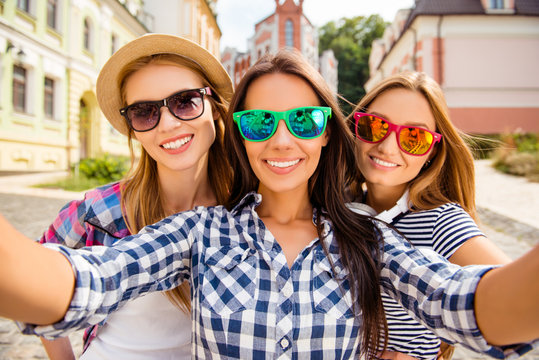 Pretty happy women in glasses making selfie in the city
