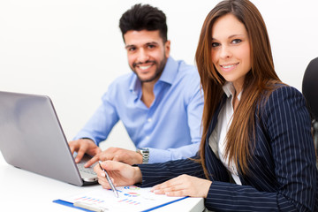     Smiling business people using a laptop computer in their office