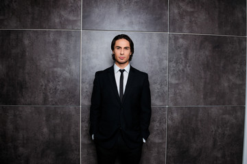 Handsome rich businessman in black tuxedo on gray background