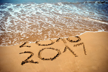 New Year 2017 is coming concept - inscription 2017 and 2016 on a beach sand, the wave is covering digits 2016. New Year 2017 celebration on New Year tropical island travel tour.