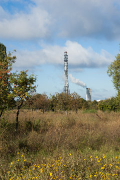 Field in autumn and industrial chimney in the background.