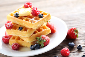 Homemade waffles with berries in plate on grey wooden table
