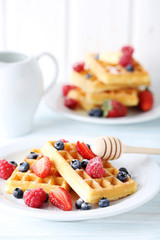 Homemade waffles with berries in plate on blue wooden table