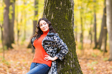 Fototapeta na wymiar autumn park, beautiful smiling woman and falling yellow leaves