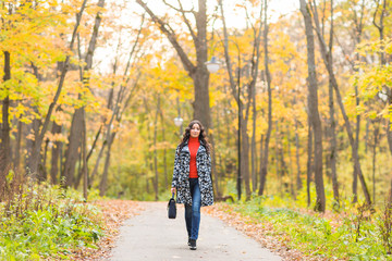 Fototapeta premium Autumn concept - Beautiful young modern woman walking in nature