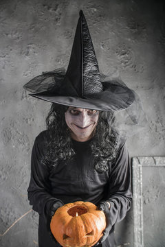 Halloween witch holding a pumpkin
