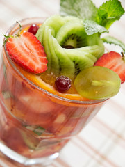 fruit salad . fruits cocktail mix of strawberry, grape, kiwi, orange, apple, pineapple and watermelon decorated with mint leaves. summer beverage