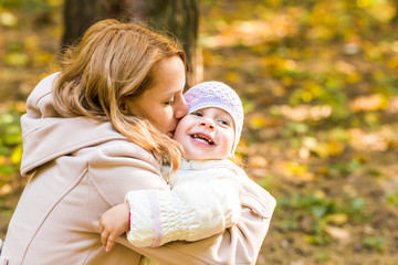 Little girl and her mother playing in the autumn park