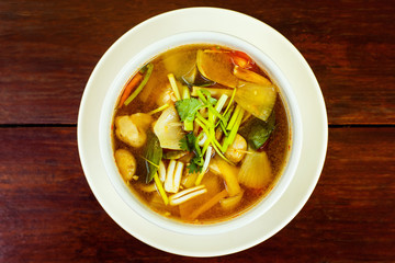 Bowl of fresh spicy hot thai soup Tom Yum at wooden table