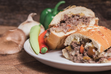 Venison stuffed french bread loaf on a white plate in rustic set