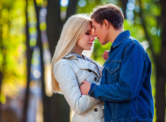 Fototapeta premium Young couple hugging in park and have closed eyes. Fall is season bring changes.