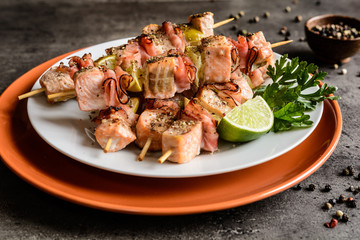 Roasted salmon skewers with smoked bacon slices and lime