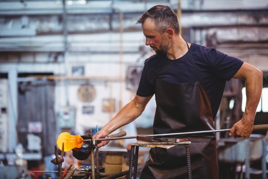 Glassblower forming and shaping a molten glass