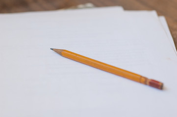 Pencil and a few sheets of white paper on the table.