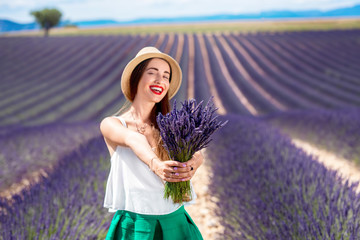 Young woman with lavender bouquet standing on the lavender field in Provence in France