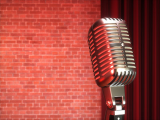 Vintage metal microphone against red curtain on empty theatre stage