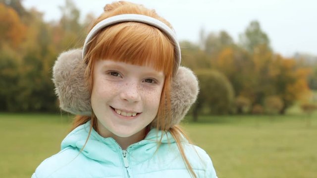 Close up ginger girl in the earmuffs winking and smiling