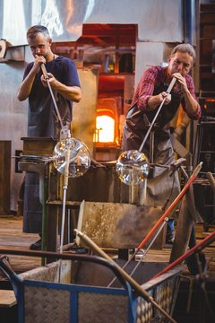 Glassblower shaping glass on blowpipe