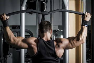 Entrenando en el gimnasio. Hombre con grandes músculos levantando peso mientras entrena en el...