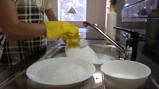 The housewife washes the dishes in the sink in the kitchen. Slow Motion. Dolly shot.