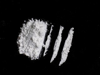 Cocaine drug powder lines and pile on black background