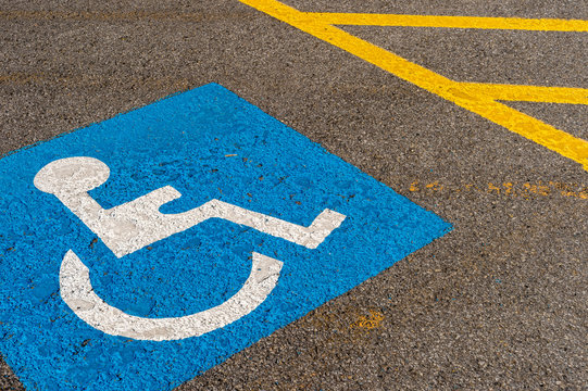 disabled blue parking sign painted on dark asphalt in Canada