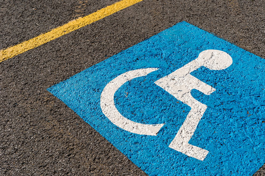 disabled blue parking sign painted on dark asphalt in Canada