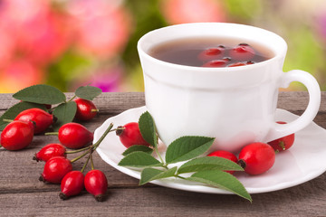 cup of tea rosehip berries on a dark wooden background