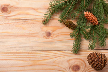Obraz na płótnie Canvas sprigs of fir with cones on a light wooden background for Christmas card