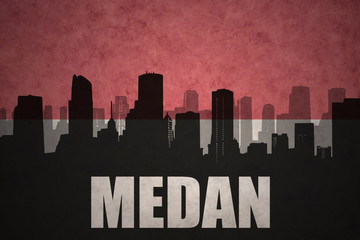 abstract silhouette of the city with text Medan at the vintage indonesian flag background