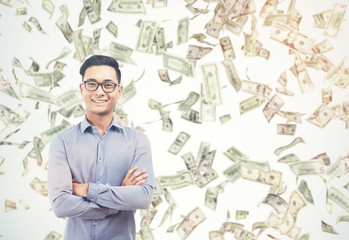 Happy Asian businessman under dollar bill rain on sunny day