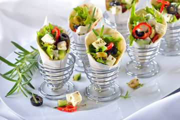 Mini-Wraps gefüllt mit griechischem Bauernsalat mit Feta und Oliven - Mini tortillas stuffed with Greek farmers salad with feta cheese and olives, served in wire egg cups