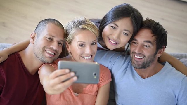 Group of friends taking selfie pictures with smartphone