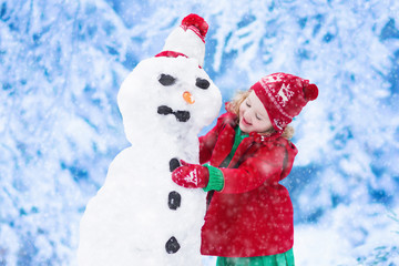 Little girl building a snow man in winter