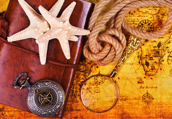 Fototapeta na wymiar old notebook, loupe and compass on the map