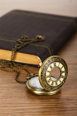 Pocket watch and book against a rustic background