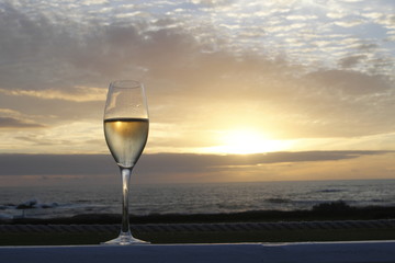 One glass of champagne during a golden sunset on an outdoor terrace overlooking the ocean