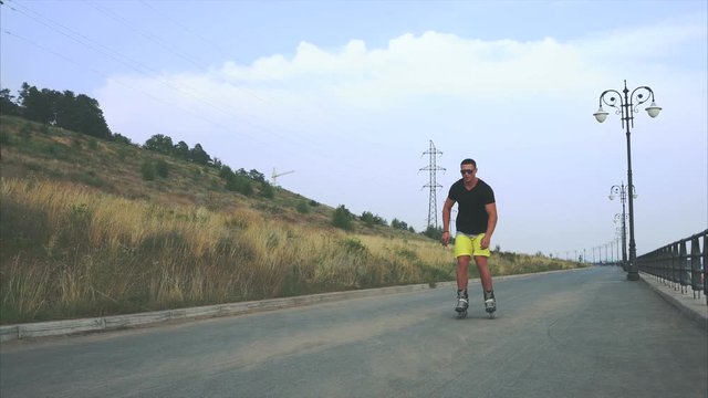 Young sporty man with inline skates ride and jump in summer waterfront 4K