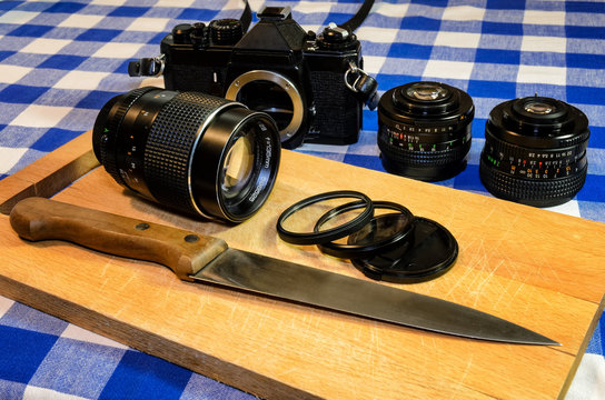 Old vintage camera and lenses on a chopping board, with filters positioned like cooking ingredients sliced with a knife