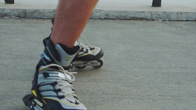 Mans legs roller skating inline close up on the asphalt 4K