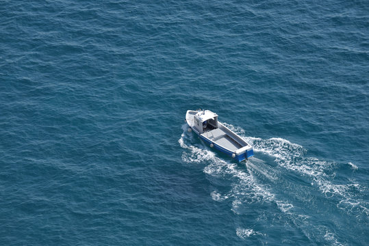 Aerial view of a white fishing boat on a blue clear sea water