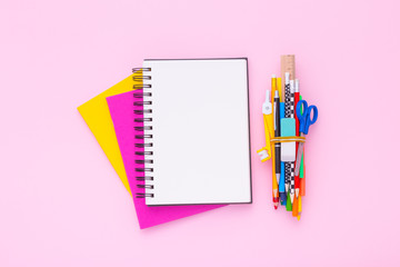 Blank notebook on a stack of colorful notebooks with scool supplies. Flat lay. Copy space.