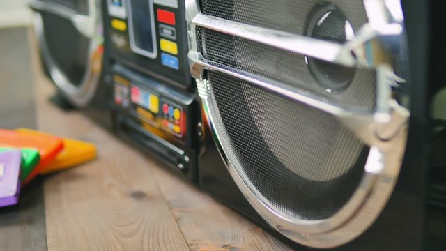 ghettoblaster stereo and old audio cassettes on wooden table dolly shot