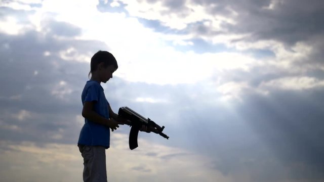 boy with a gun at night on the background of beautiful clouds, ak 47