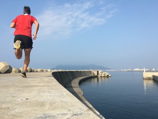 Male runner in red shirt on sea wall