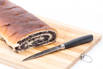 Strudel with poppy seeds on the wooden board with knife