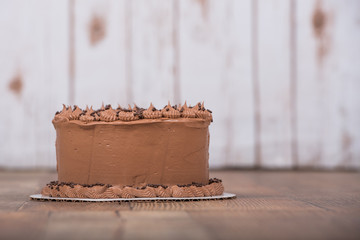 Chocolate frosted cake with wood background and table